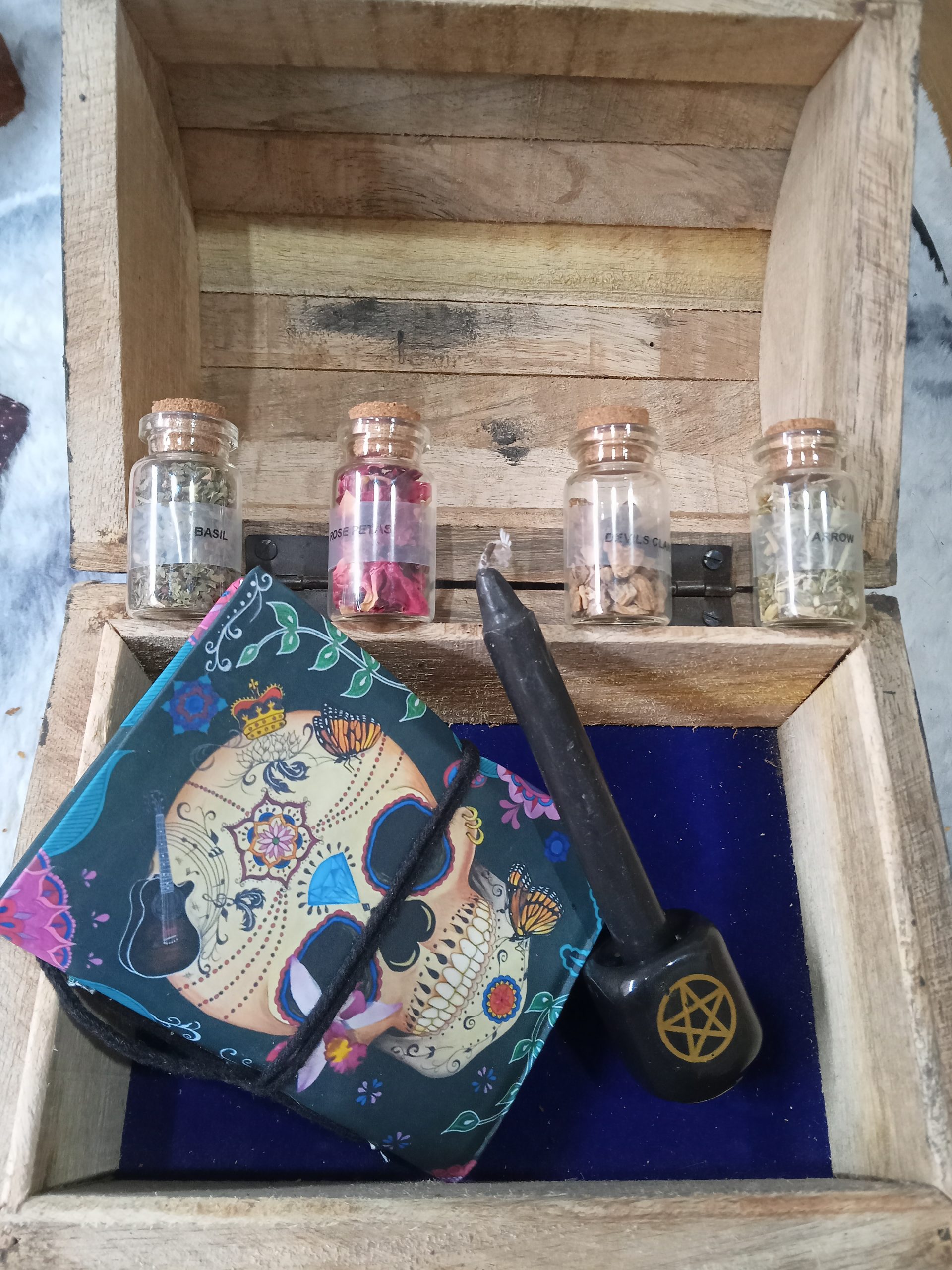 A wooden box with herb bottles and candles inside